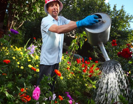 Workers wearing PPE while operating lawn care machinery in a residential garden